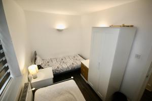 a small white bedroom with a bed and a cabinet at Bournemouth Hot Tub & Sauna Holiday Let in Bournemouth