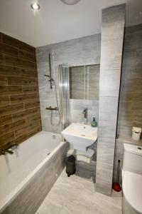 a bathroom with a sink and a tub and a toilet at Bournemouth Hot Tub & Sauna Holiday Let in Bournemouth