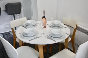 a white table with chairs and a bottle of wine at Bournemouth Hot Tub & Sauna Holiday Let in Bournemouth