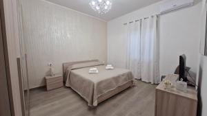 ein weißes Schlafzimmer mit einem Bett und einem TV in der Unterkunft Casa Vacanze sul Corso in Giarre