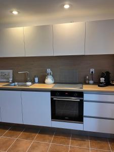 a kitchen with white cabinets and a stove and a sink at A cosy basement apartment in Hluboká nad Vltavou +1 photo