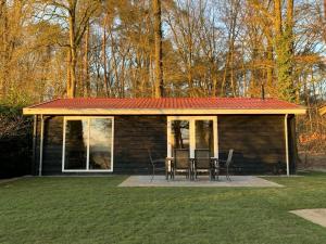 een kleine hut met een rood dak en een tafel en stoelen bij De Hooischuur in Hellendoorn