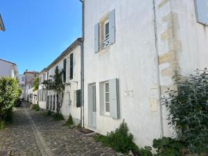 eine Gasse mit einem weißen Gebäude mit Fenstern in der Unterkunft Maison de village L'A N N E X E proche du port in Saint-Martin-de-Ré