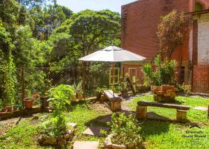 a garden with an umbrella and a bench at Gramado Guest House in Gramado
