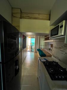 een keuken met een fornuis bovenste oven naast een woonkamer bij APARTASUITE A UN PASO DEL MAR in Tolú