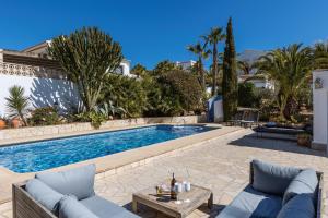 uma piscina com dois sofás azuis e uma mesa em Casa Nero em Xàbia