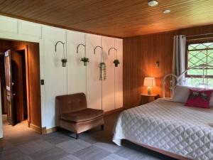 a bedroom with a bed and a chair and a window at Auberge Les Sources in La Malbaie