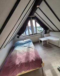 ein Schlafzimmer mit einem Bett und einem Sofa im Dachgeschoss in der Unterkunft Messezimmer am Thewissenweg in Düsseldorf