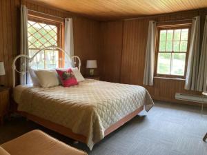 a bedroom with a bed and two windows at Auberge Les Sources in La Malbaie