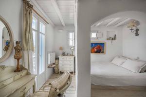 a white bedroom with a bed and a mirror at Samanti House, Leivadi Serifos in Livadi