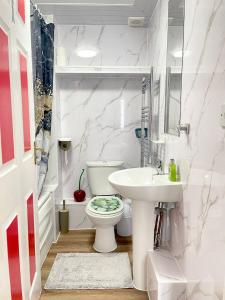 Westfield Grove 3 Bedroom Apartment في Goodmayes: حمام به مرحاض أبيض ومغسلة