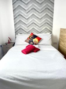 Westfield Grove 3 Bedroom Apartment في Goodmayes: سرير ابيض عليه وسادتين حمر