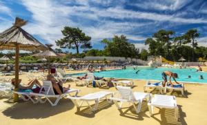 a group of people sitting in chairs at a swimming pool at Large Mobile Home on 4star Camping in Capbreton