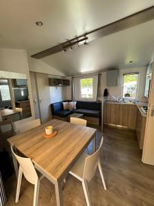 a living room and kitchen with a wooden table and chairs at Large Mobile Home on 4star Camping in Capbreton
