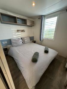 a bedroom with a bed with two slippers on it at Large Mobile Home on 4star Camping in Capbreton