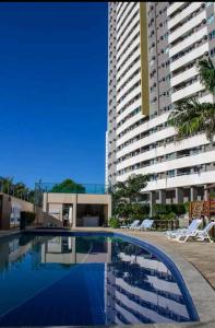 a swimming pool in front of a tall building at Excelente apartamento Verano Ponta Negra 02 in Natal