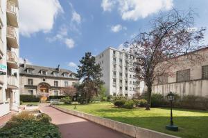 a large white building with a grassy yard next to a building at Charenton View Paris Door Best Location metro in Charenton-le-Pont