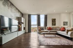 ein Wohnzimmer mit einem Sofa und einem TV in der Unterkunft Stunning 360º View Luxurious Penthouse in London