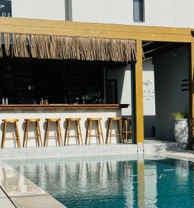 un bar con taburetes junto a una piscina en Ikaros Suites, en Amoudara Herakliou