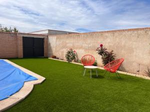 zwei rote Stühle und ein Tisch in einem Hof in der Unterkunft Un sueño en Toledo II, al lado de Puy du Fou in Argés