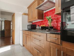 a kitchen with wooden cabinets and a red tile wall at 6 Sydney Road in Ramsgate