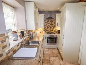 een keuken met witte kasten en een wastafel bij Erin Cottage formerly Chloe's Cottage in Keighley