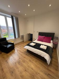 a bedroom with a large bed and a black chair at See the Sea Hideaway in The Mumbles