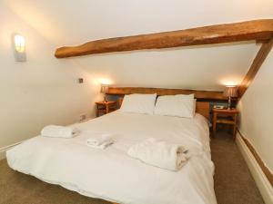 a bedroom with a large white bed with towels on it at Saddleback Barn in Penrith