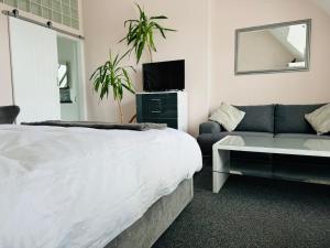 a bedroom with a bed and a couch and a mirror at Penthouse Suite, Central St Leonards, Sea View in St. Leonards