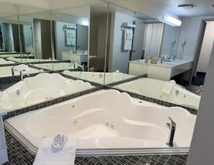 a bathroom with a large tub and mirrors at Divya Sutra Plaza and Conference Centre Calgary Airport in Calgary