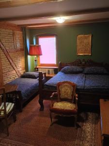 a bedroom with two beds and a chair and a window at Pokoje Złotoryja in Złotoryja