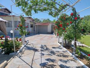 a garden with roses and a pergola at Villa Artzie. Έξοχικο με τεράστιο εξωτερικό χώρο. in Nea Kallikrateia