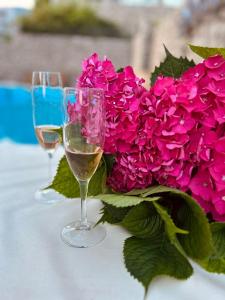 twee glazen wijn naast een boeket roze bloemen bij Apartman Djordje in Budva