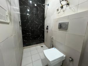 a bathroom with a toilet and a black tile wall at Hotel Model Town Metro View in New Delhi