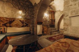 a room with a stone wall with a table in it at Anatolia Raymonde Cave House in Uçhisar