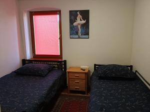 a bedroom with two beds and a window with a dresser at Pokoje Złotoryja in Złotoryja