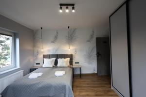 ein Schlafzimmer mit einem Bett und einer Wand mit Pflanzen in der Unterkunft JAK MAKIEM ZASIAŁ in Jastrzębia Góra