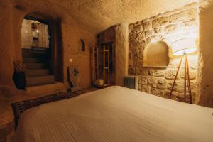 a bedroom with a bed in a stone wall at Anatolia Raymonde Cave House in Uchisar