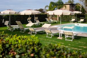 a group of chairs and umbrellas next to a pool at Agriturismo Acquachiara in Sabaudia