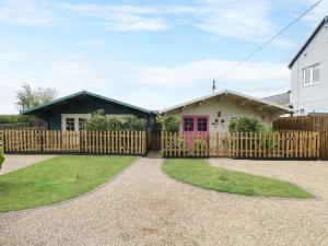 uma casa com uma cerca e uma porta rosa em The Log Cabin em Swindon