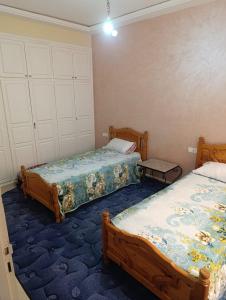 - une chambre avec 2 lits et un tapis bleu dans l'établissement appartement berkane, à Berkane