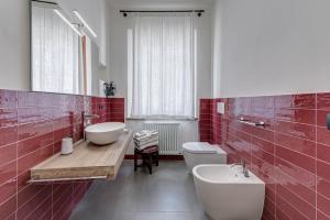 y baño con azulejos rojos, lavabo y aseo. en BORGO SAN QUIRICO D'ORCIA B&B - Capitano Collection - Albergo diffuso, en San Quirico dʼOrcia