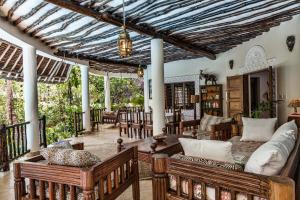 an outdoor living room with wooden furniture and a pergola at Diani Villa in Diani Beach