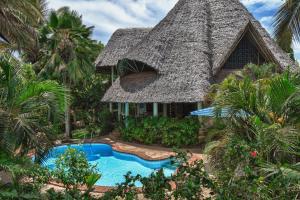 ein Resort mit einem Strohdach und einem Pool in der Unterkunft Diani Villa in Diani Beach