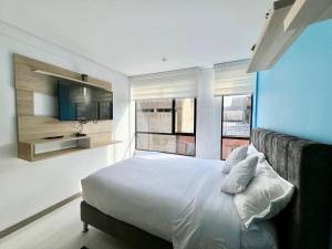 een slaapkamer met een bed en een televisie en een aantal ramen bij Maravillosos apartamentos en Chapinero Weeki in Bogota