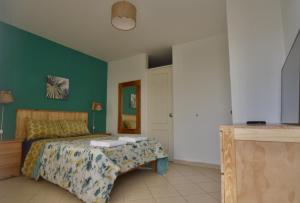プンタ・エルモサにあるCasa mar surfhouseの緑の壁、ベッド付きのベッドルーム1室