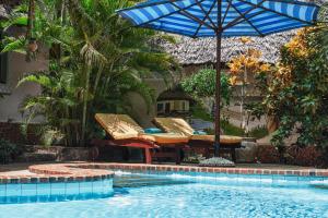 a pool with a blue umbrella and chairs and a table at Diani Villa in Diani Beach