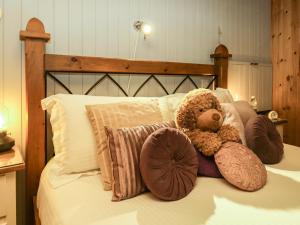 Lake Lodge Studio في باونيس أون وينديرمير: وجود دبدوب يجلس على سرير مع وسائد