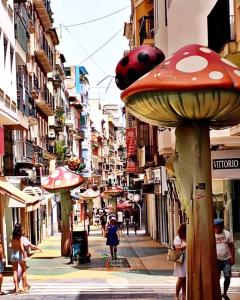 a group of people walking down a city street with a mushroom sign at Carlota in Alicante