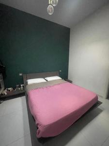 1 dormitorio con cama rosa y pared verde en Manu's House Villetta Indipendente, en Monte di Procida